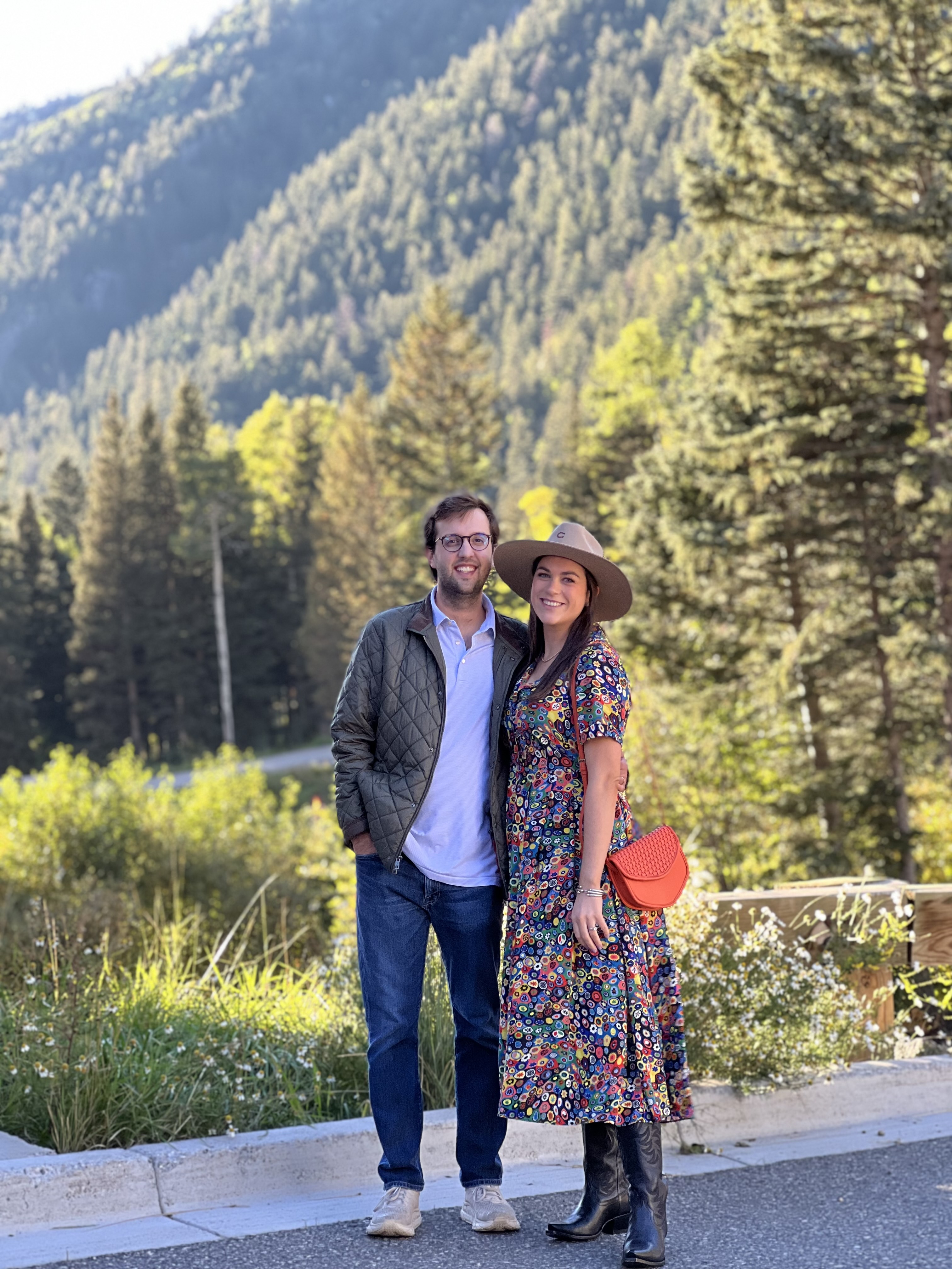 Grant Borelli and his wife pose in front of a mountainous landscape.