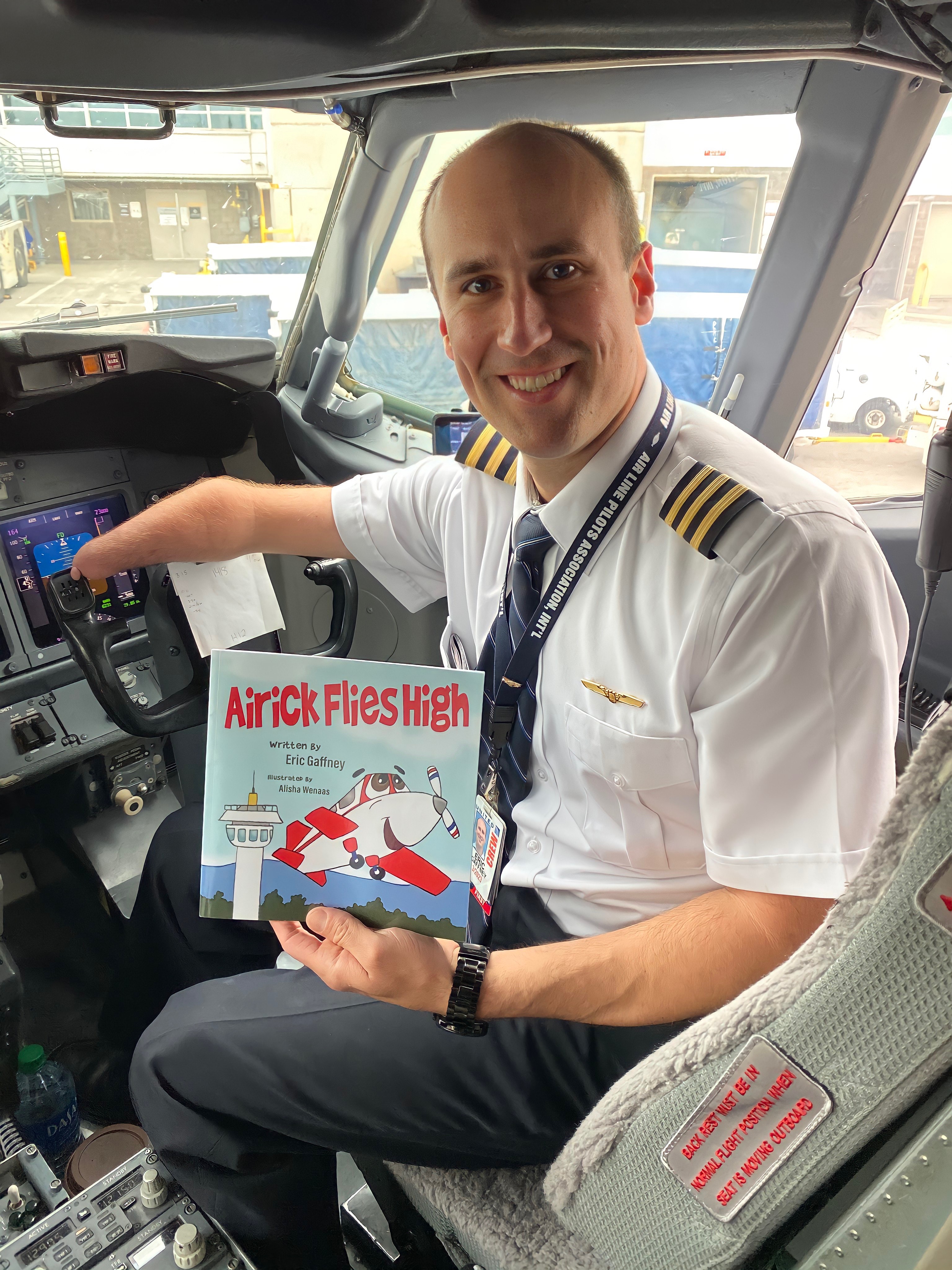 Eric Gaffney hold his children's book "Airick Flies High" in the cockpit of a plane.