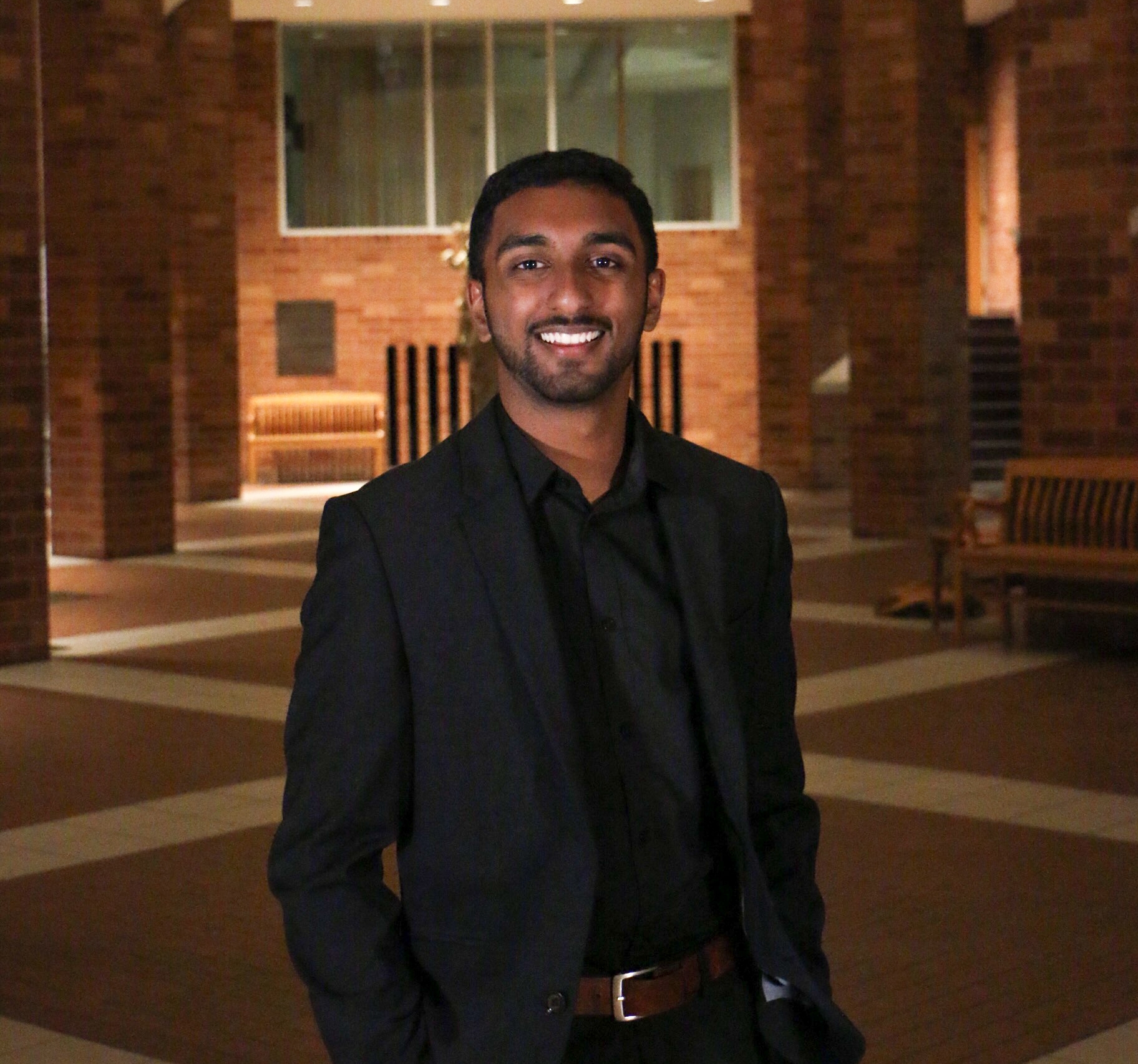 PLC Student Andrew Jacob smiling in a black suit inside of Catlett Music Hall.