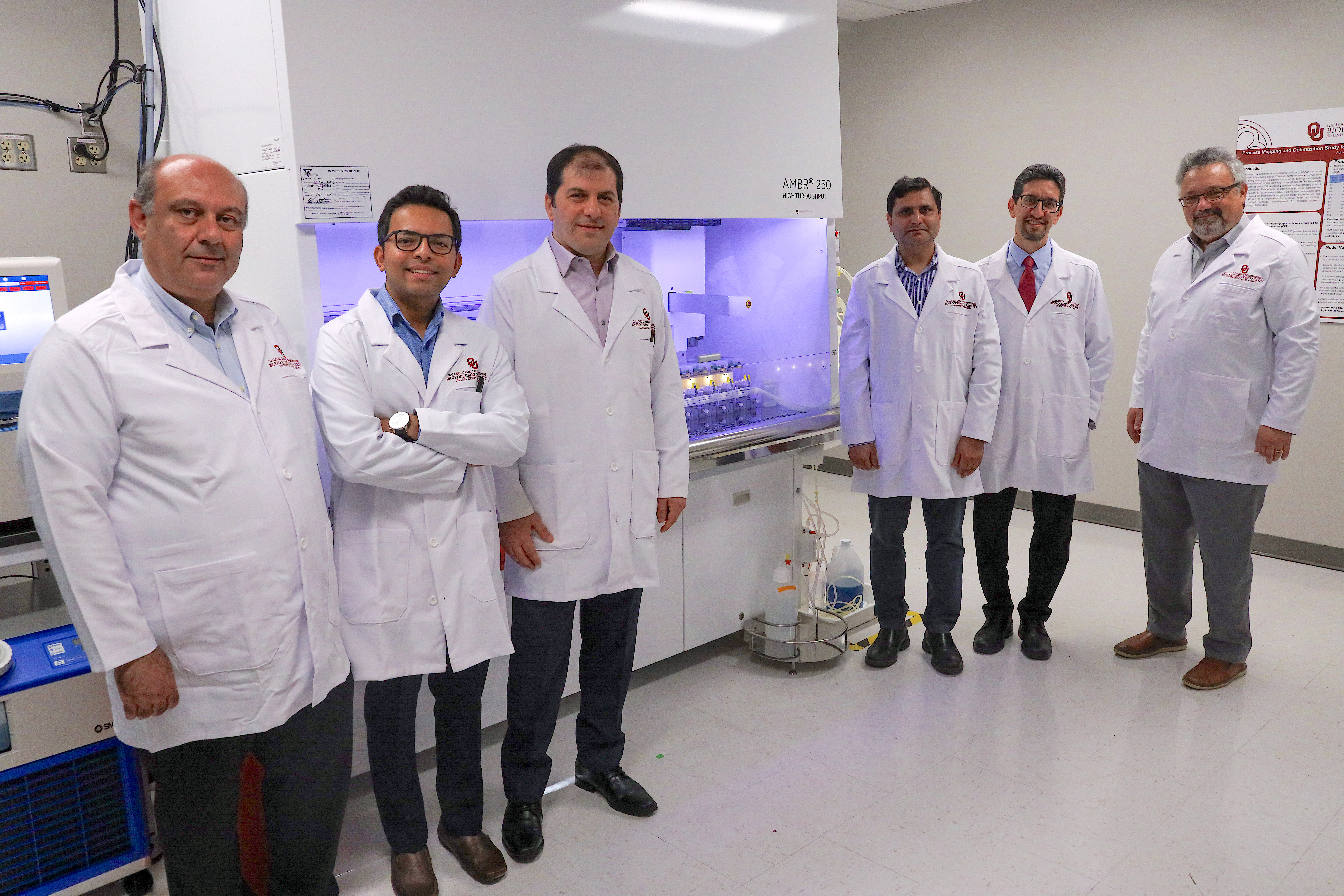 Researchers gathered around the OU Bioprocessing Core Facility Ambr 250 HTP 12-Way System.
