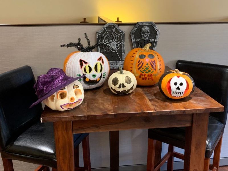 Five painted pumpkins of various sizes on a wooden table. 