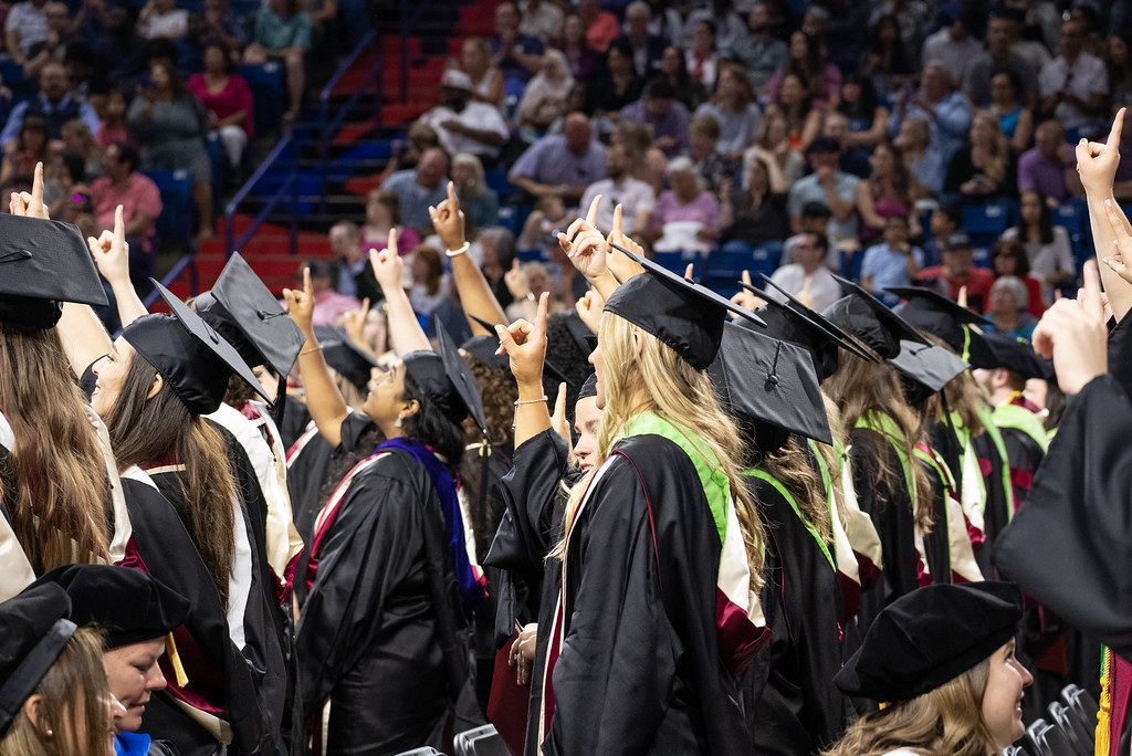 OU-Tulsa students hold up one finger at graduation.
