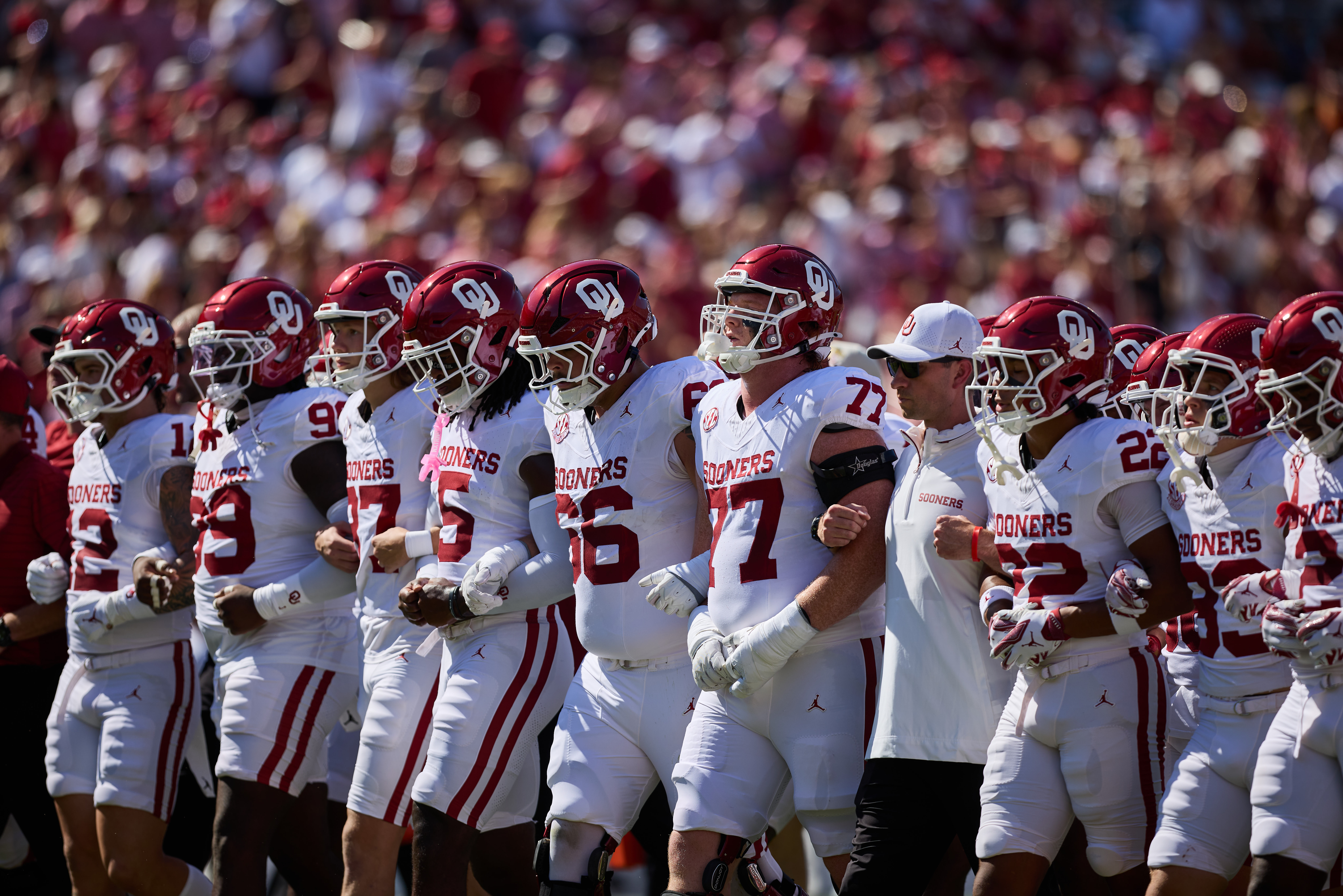 O U players walk in line with arms interlocked