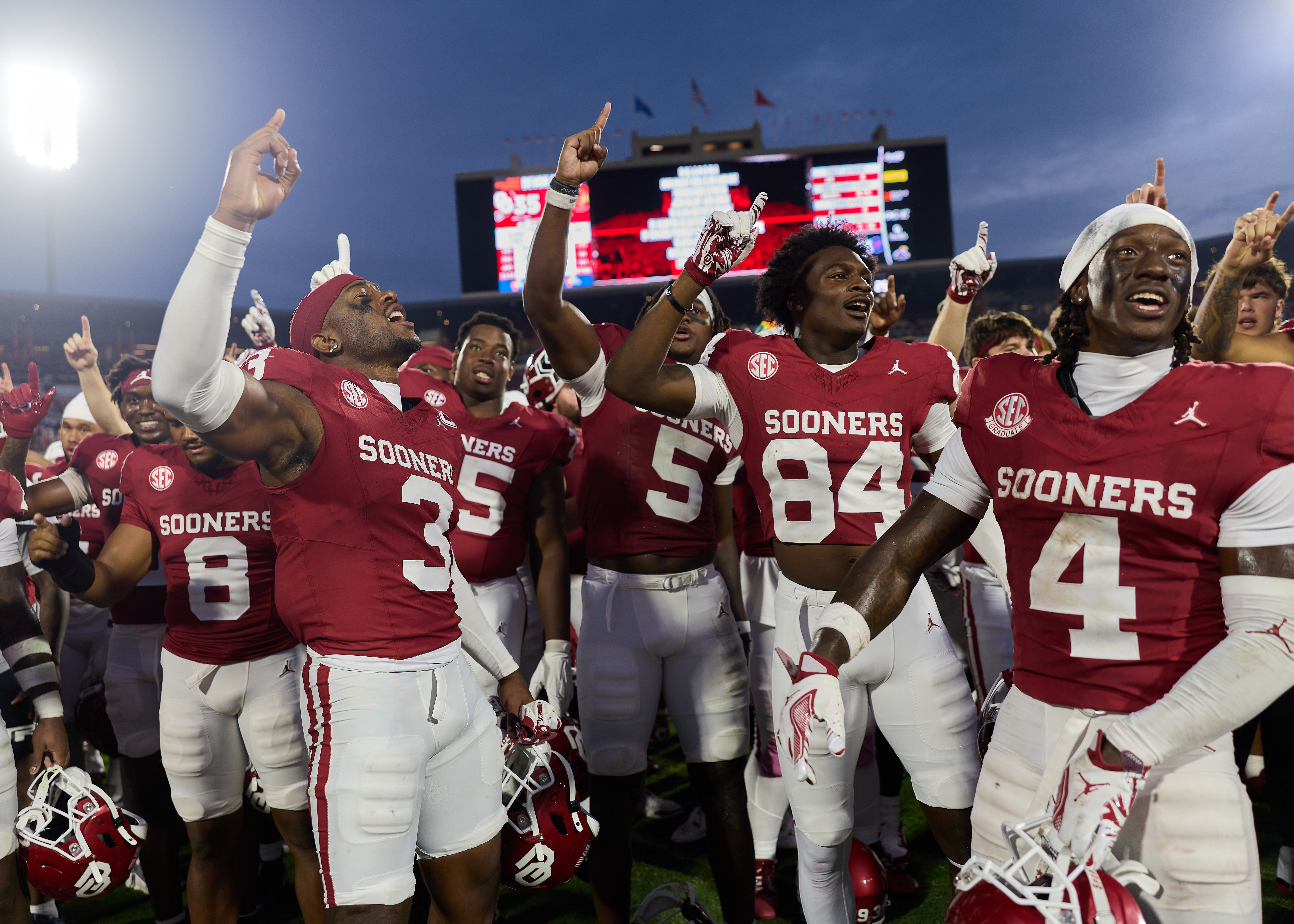 O U football players stand in crowd with fingers in the air holding up a one signal