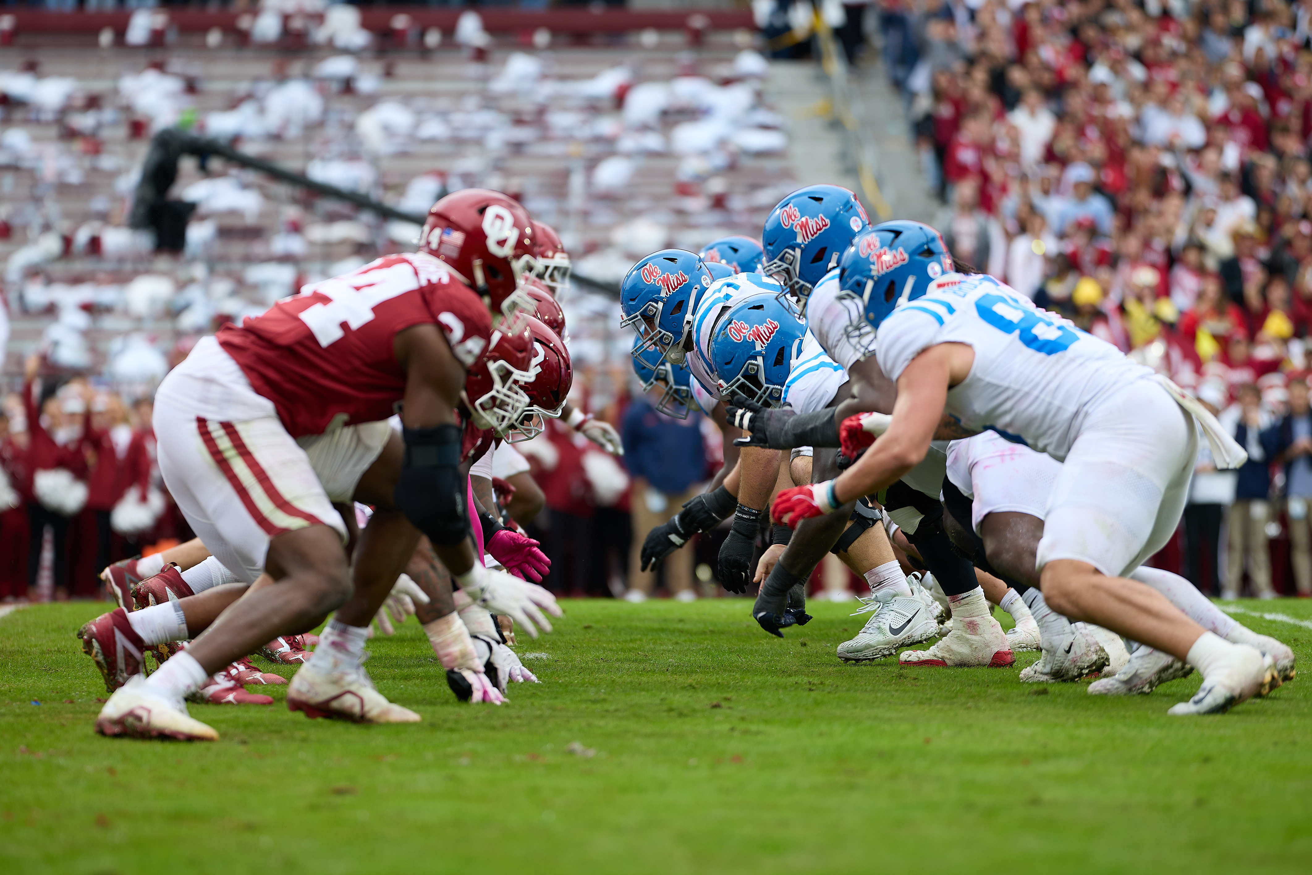 O U and Ole Miss football players are lined up head to head at the line of scrimmage during football game