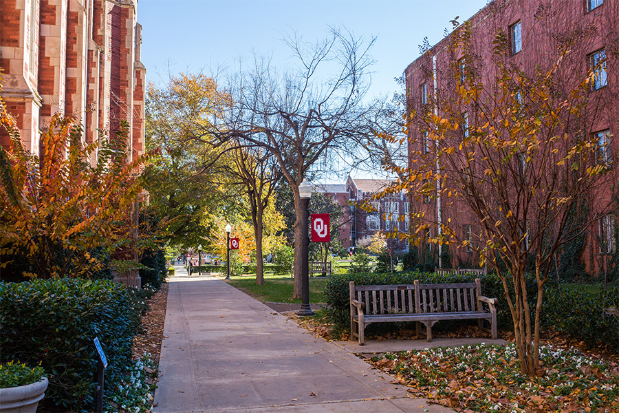 Walkway going between two buildings with fall foliage around.