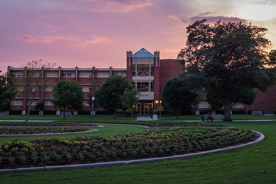 Collings Hall at sunset, surrounded by greenery.