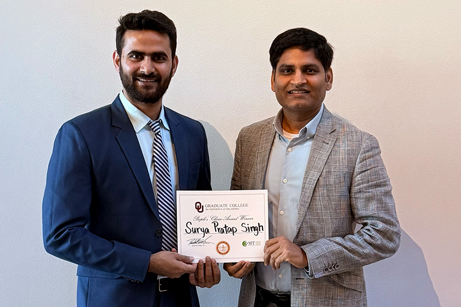 Surya Singh holding award with OU faculty member.