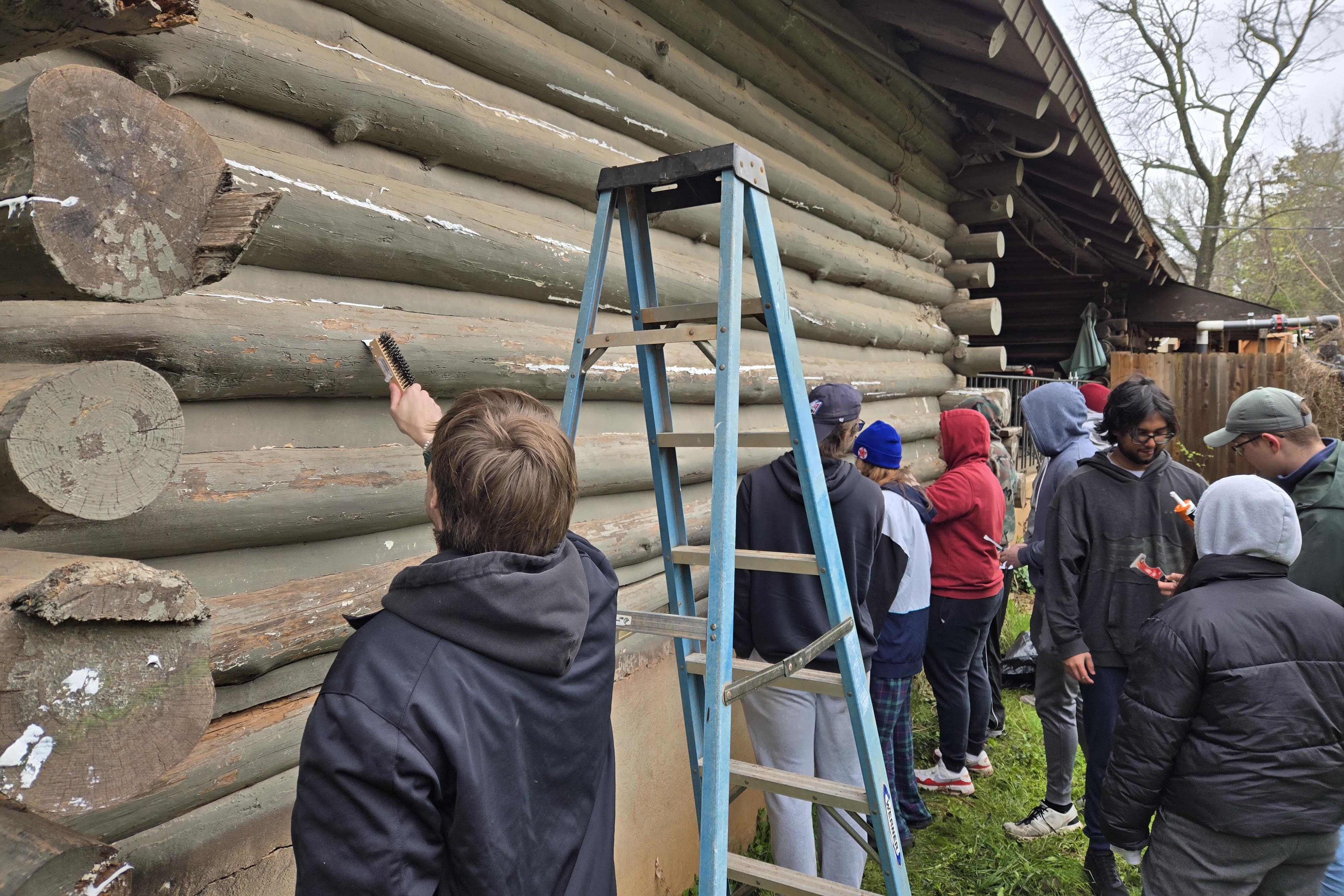 Econ Club scraping old paint from an old cabin. 
