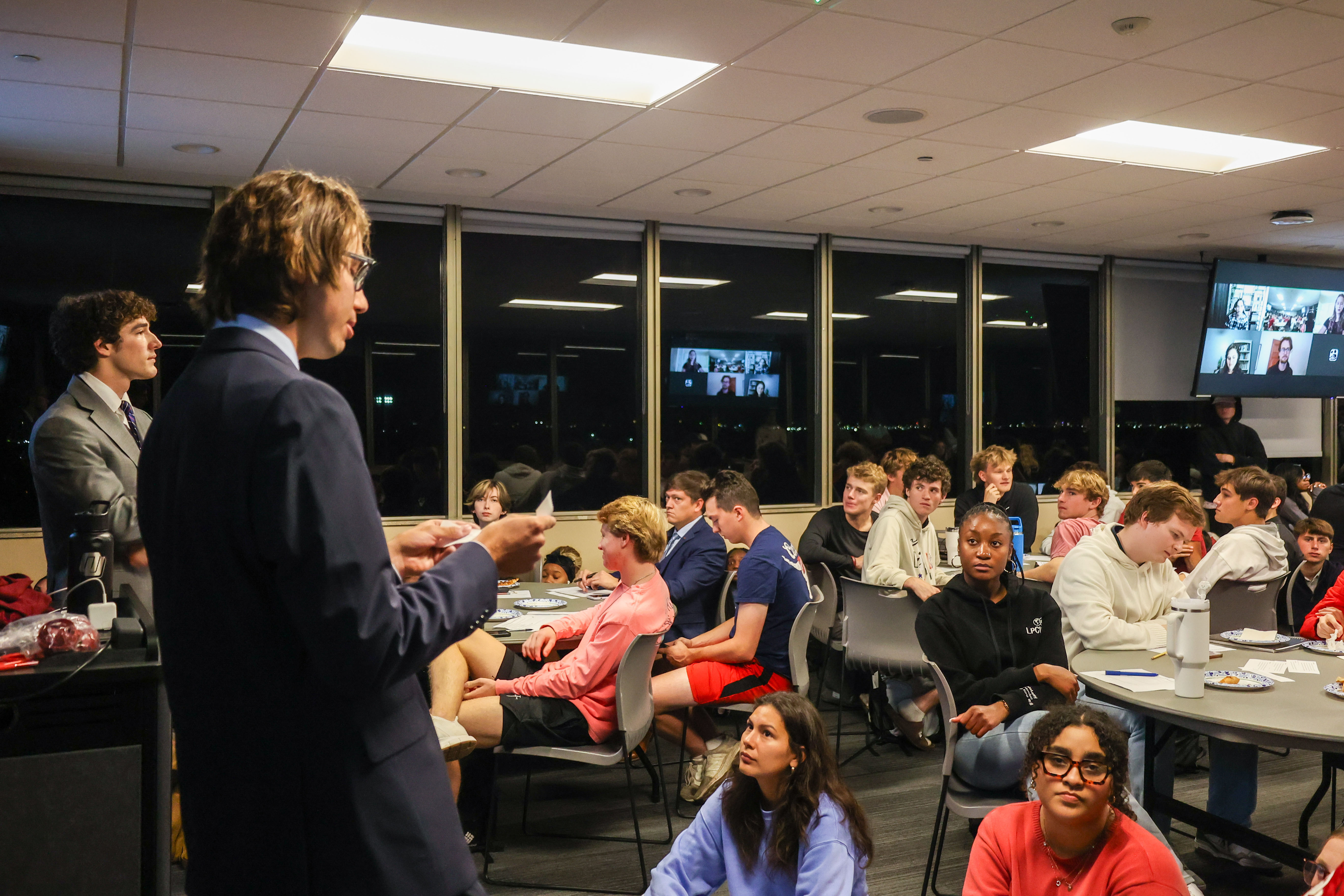 Man reading in front of group of students. 