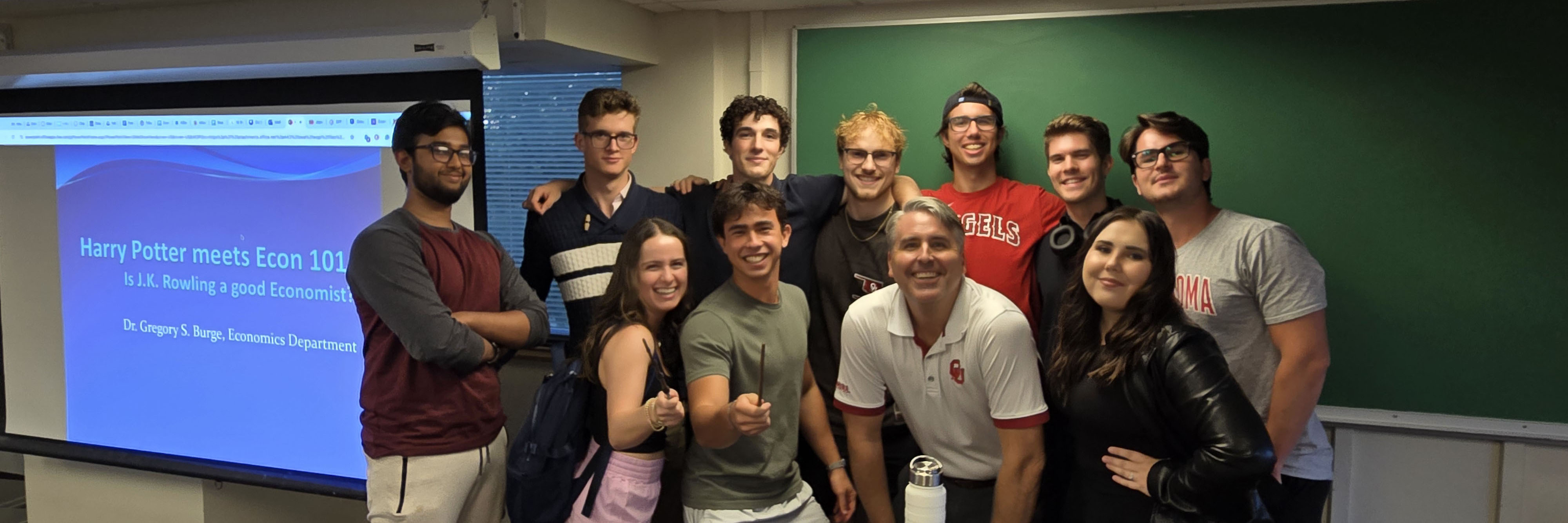 Econ club posing with Dr. Burge pointing Harry Potter wands at the camera. 