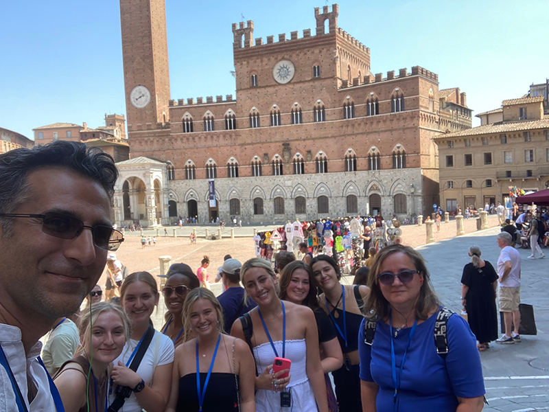 Dr. Demir and Dr. Kosmopoulou with a group of students in front of a building. 