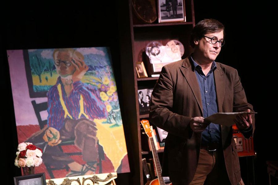 A performance of "More Sky!" featuring a speaker next to pieces of art.