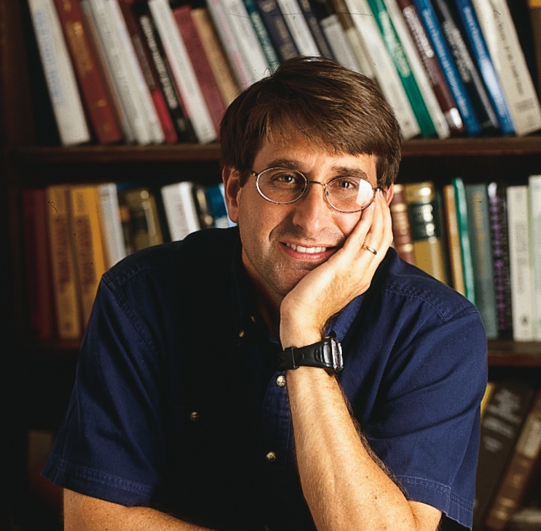A photo of Bruce Mason in front of a bookcase.
