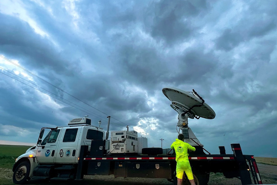 A scientist configures a radar on a large truck toward and incoming storm.