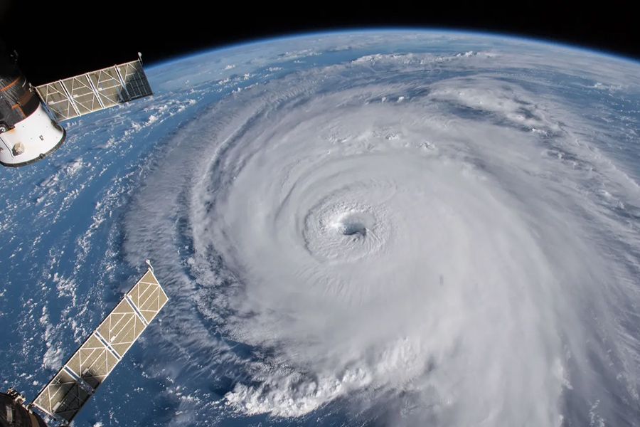 A view of space, showing satellites orbiting around Earth, showing a massive hurricane, depicted by spiraling clouds.
