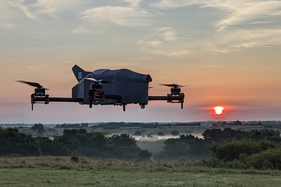 A CopterSonde, which is a weather drone, flies across the landscape with the sunseting in the background.