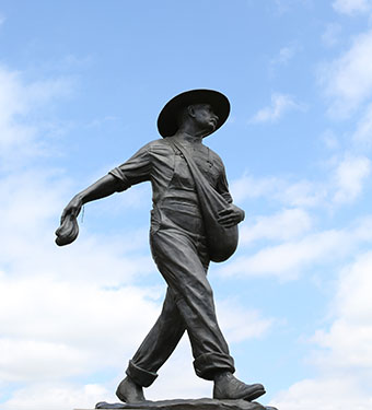 Statue of man in a broad hat sowing seed.