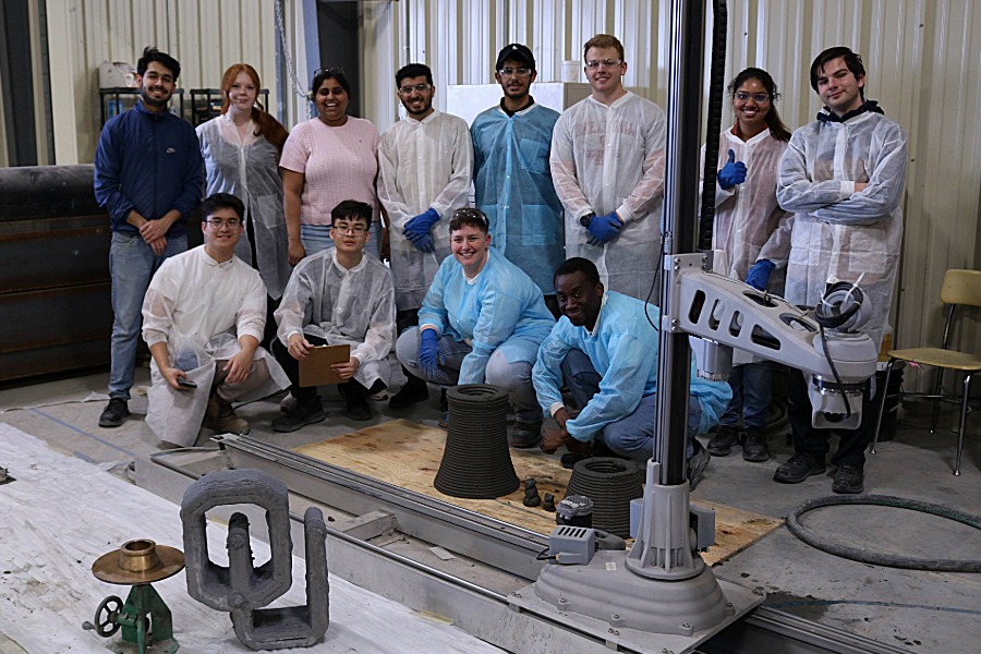 Students in the 3D Concrete Printing Workshop pose around a custom O U statue. 