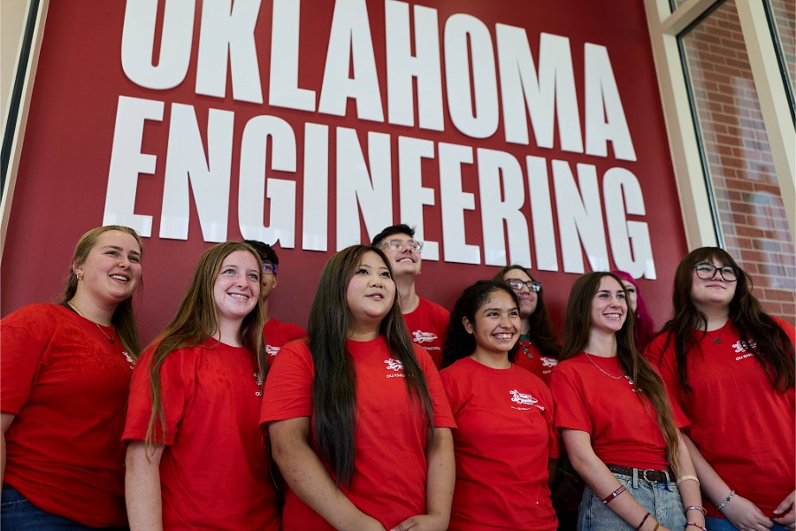 Students standing in front of a sign that says 'Oklahoma Engineering'.
