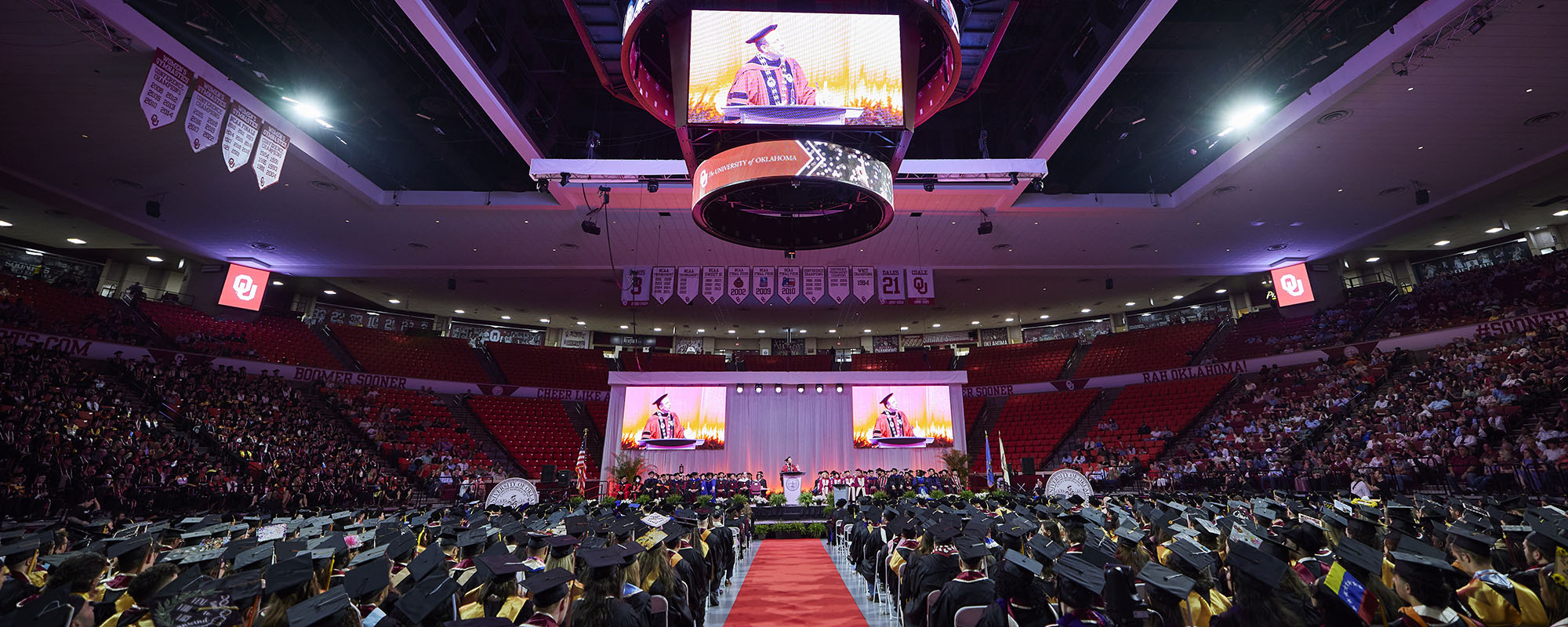 The interior of the Lloyd Noble Center, completely filled with students in graduation regalia.