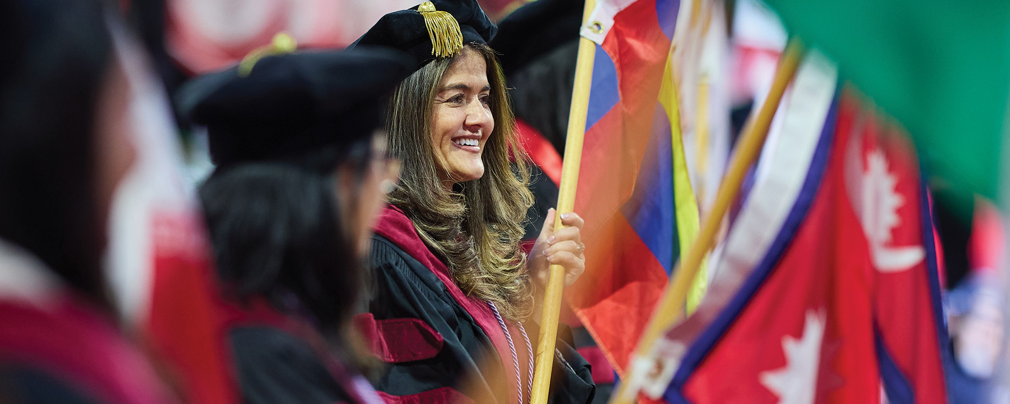 Two people in regalia embracing at a commencement celebration.
