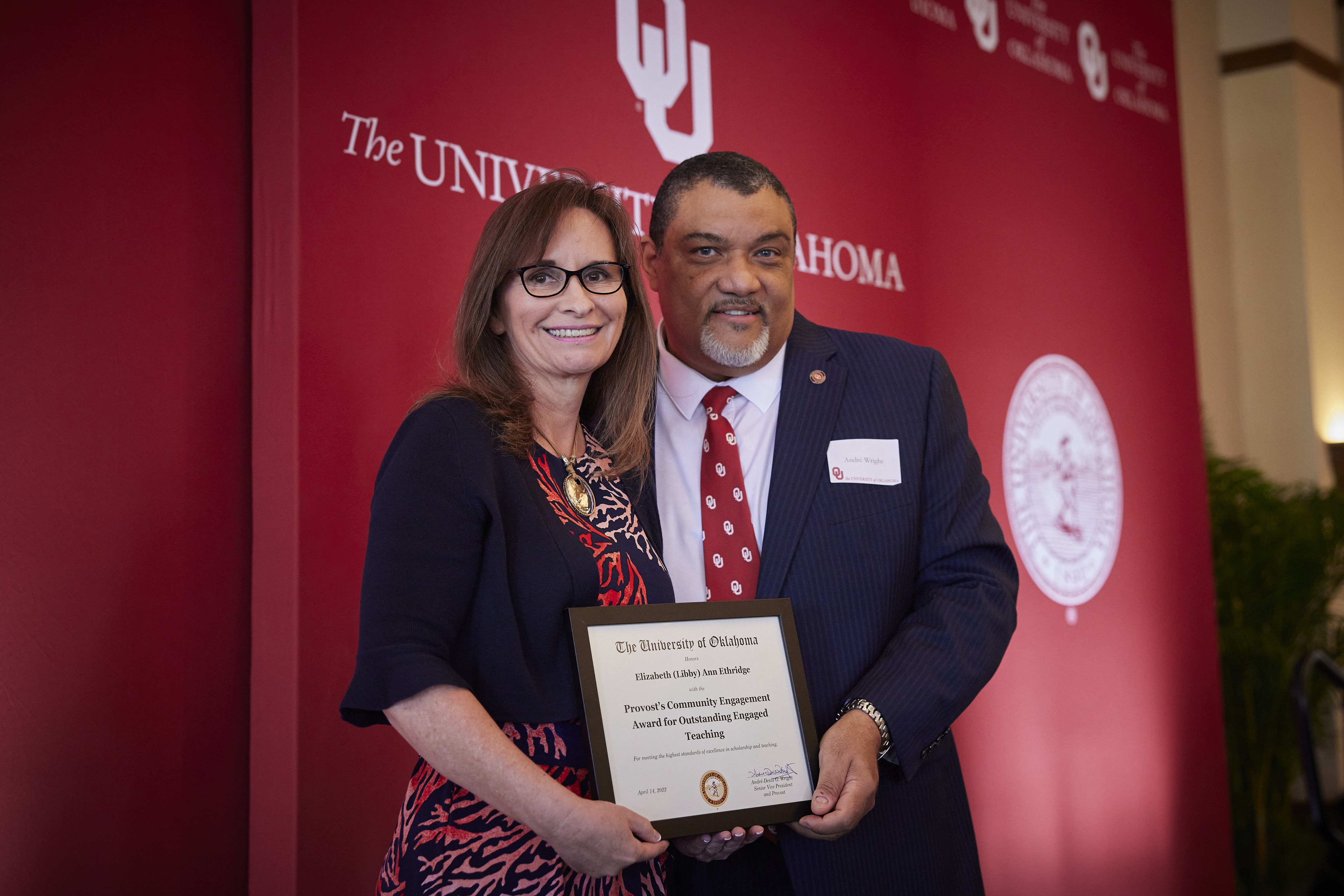 Libby standing with Provost Wright while holding a plaque