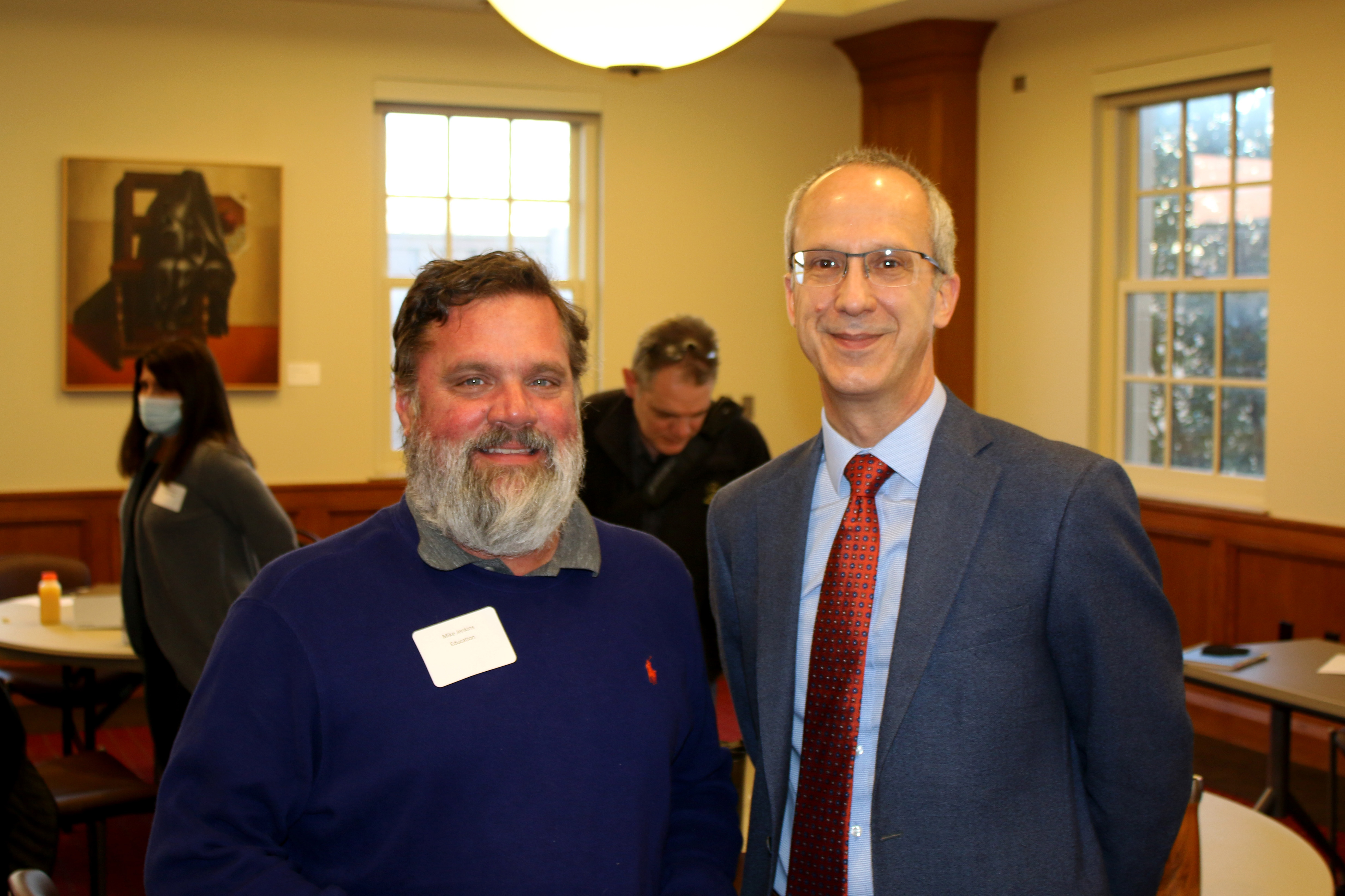 Mike Jenkins in a blue sweater standing next to graduate college member