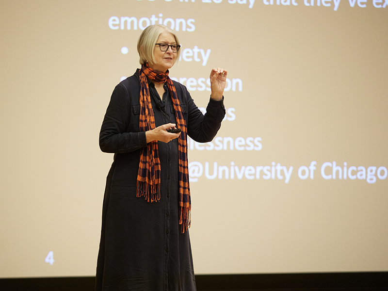 Woman in a black dress with red scarf standing on a stage in front of a screen