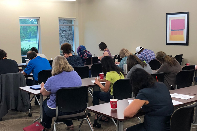 Teachers in a classroom writing at desks