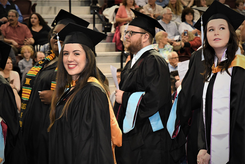 student wearing cap and gown smiling at camera