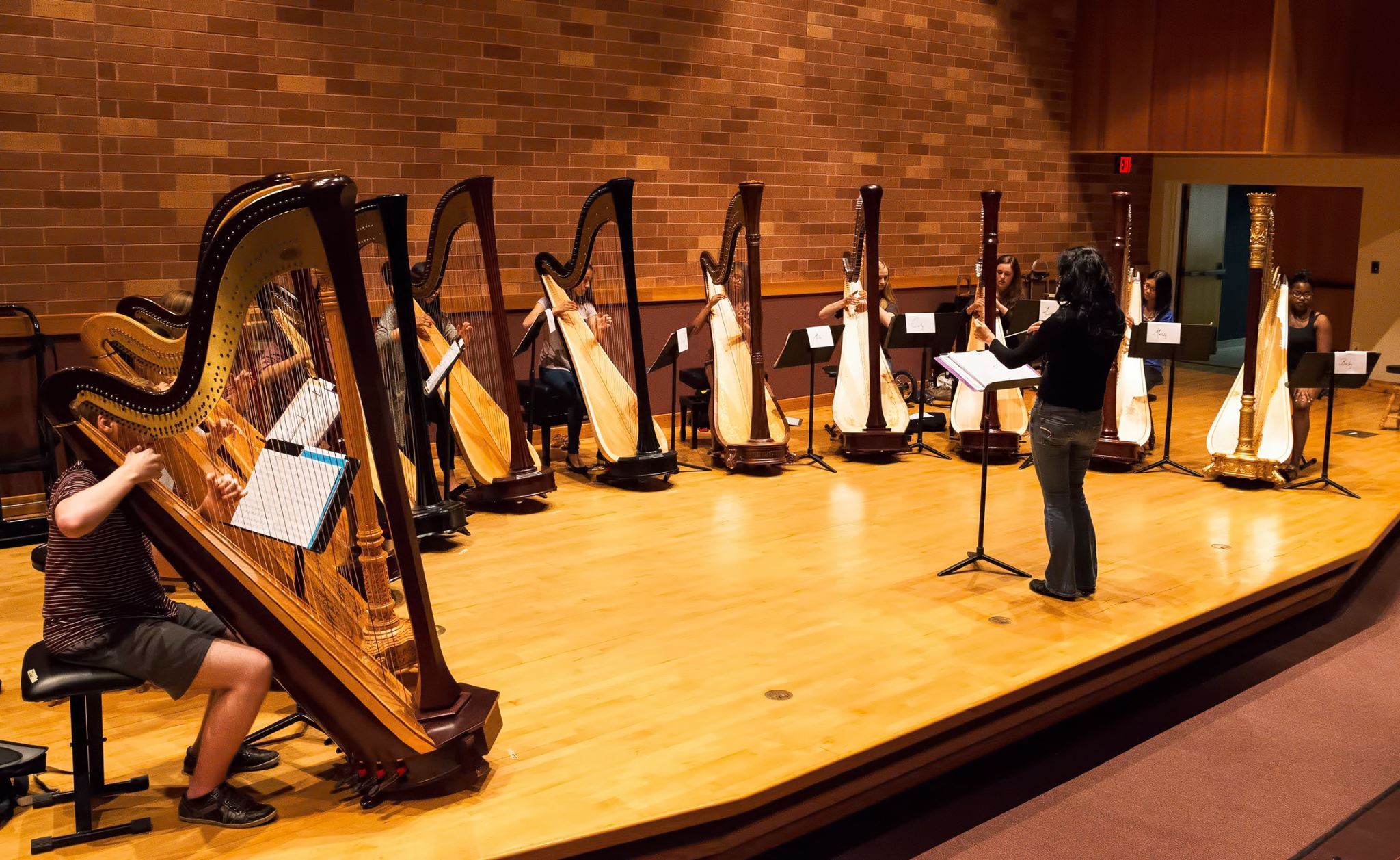 OU Harpists and harp camp attendees perform on stage in Pitman Hall.