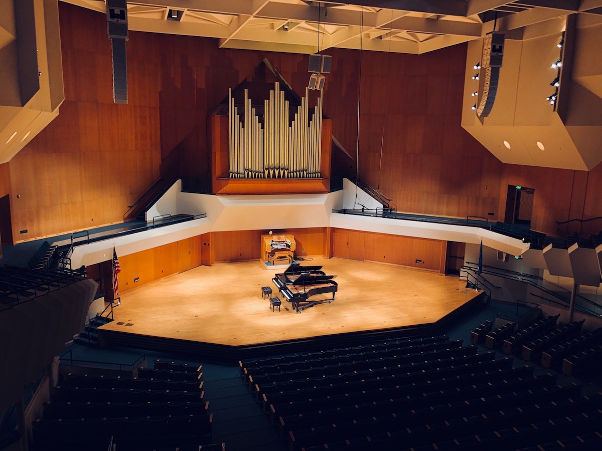 Empty Sharp Hall from audience perspective with 2 grand pianos on stage.