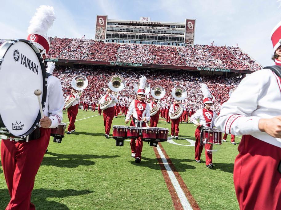 Pride of Oklahoma drumline and sousaphones in formation on the field.