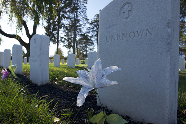 A graveyard headstone with the word "unknown" and a cross engraved onto it.