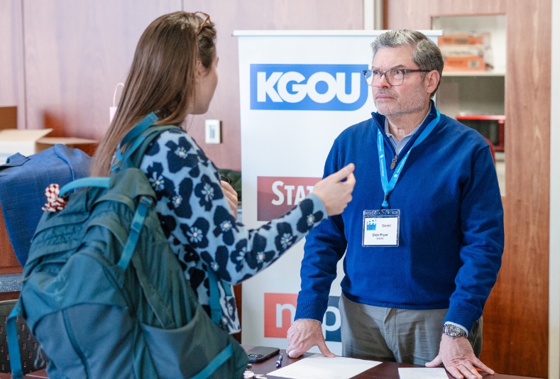 Student at media marketplace speaking with KGOU rep.