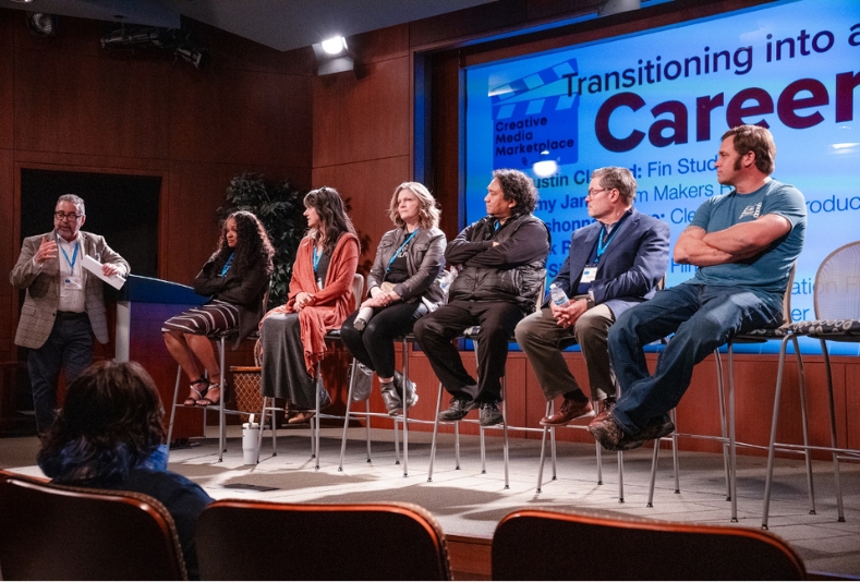 Student at media marketplace speaking with KGOU rep.