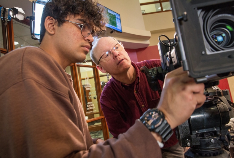 Student working with instructor with camera.