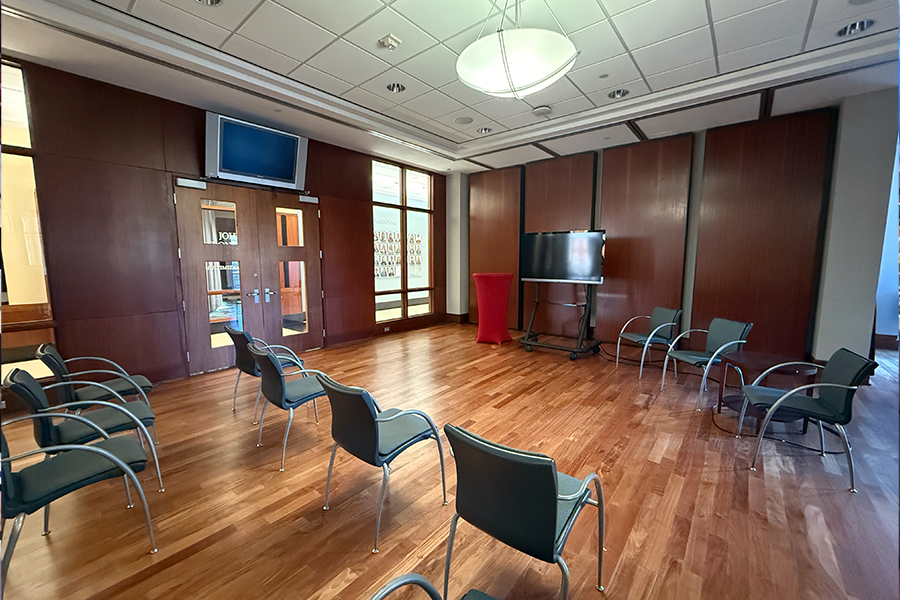 The National Weather Center Boardroom, with a large table an chairs in the middle and flags and a projection screen in the back.
