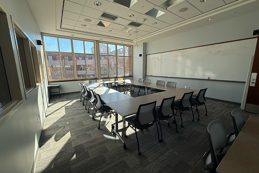 The National Weather Center Boardroom, with a large table an chairs in the middle and flags and a projection screen in the back.