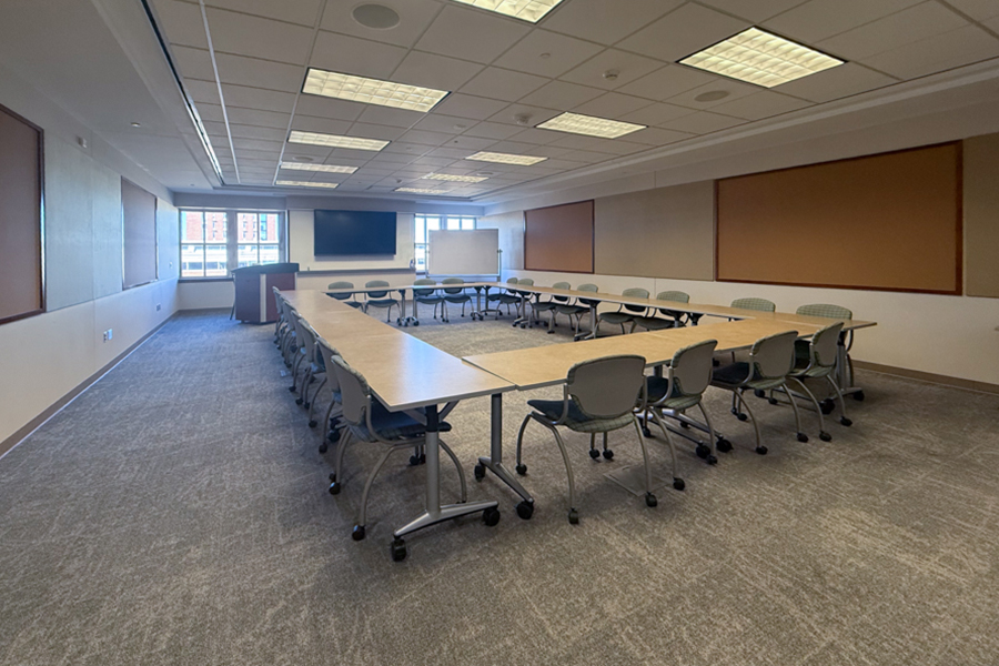 The National Weather Center Boardroom, with a large table an chairs in the middle and flags and a projection screen in the back.