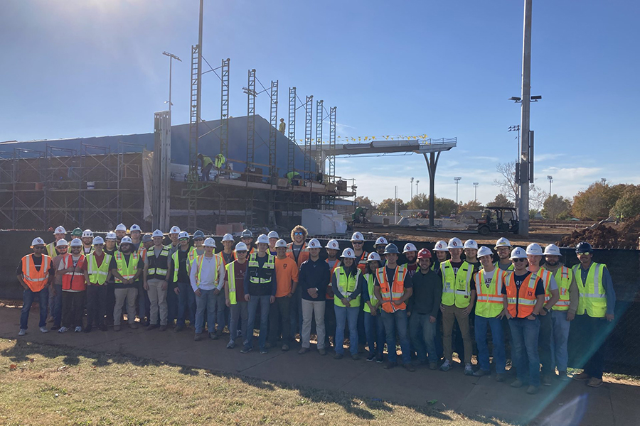 Construction Science students posing for a photo in front of a softball field that is under construction.