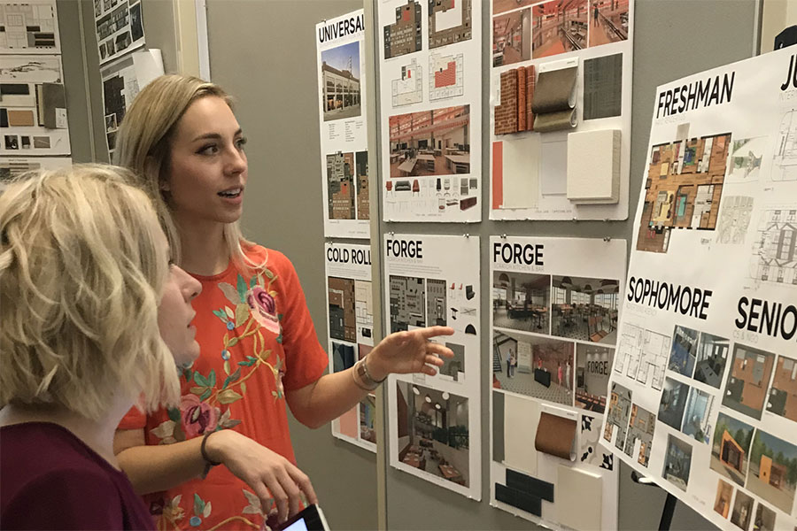 Two people looking at posters on a wall.