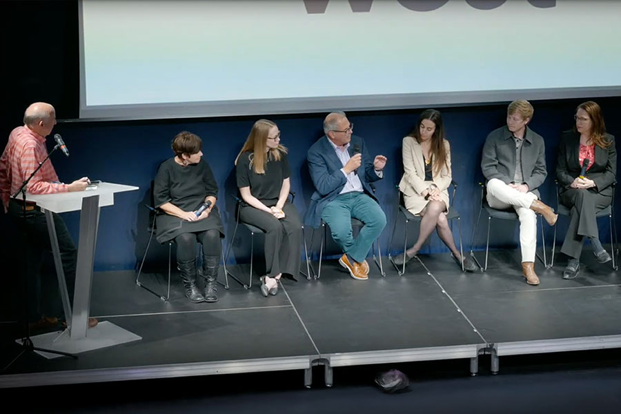 A panel of people on stage, with Alan Hess at the podium.