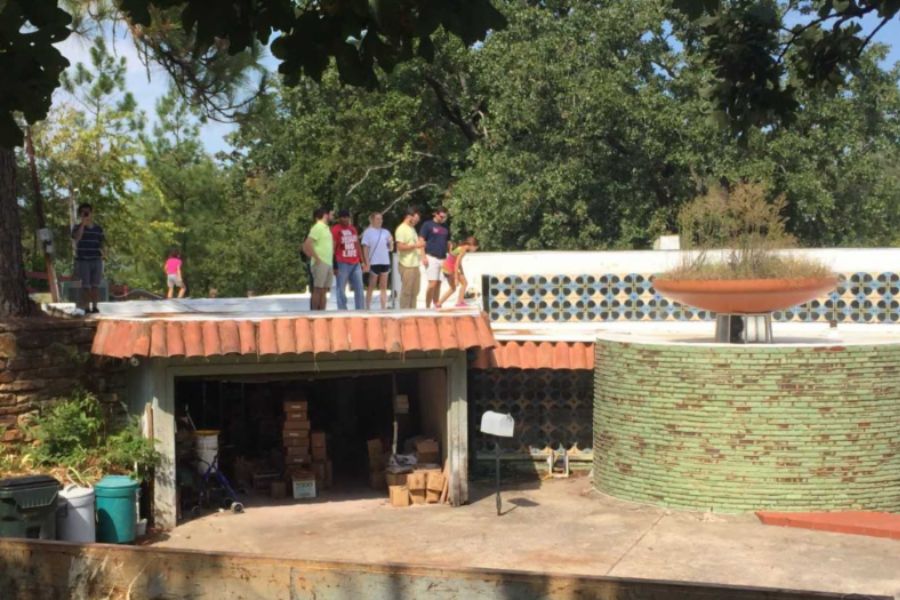 Photo of a driveway to a modern looking house with people standing on the roof examining the architecture