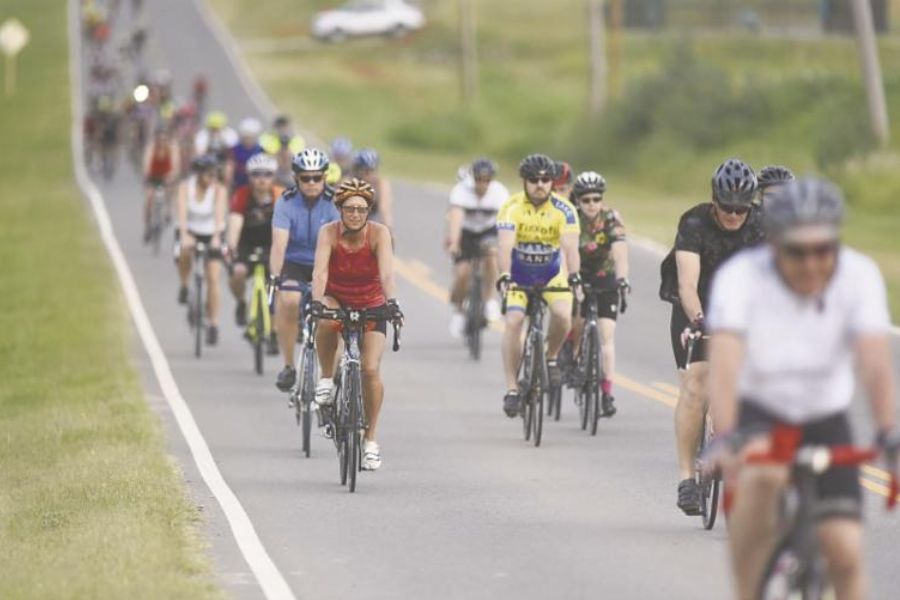 A group of 20 plus individuals riding cycles in a bike race on a road