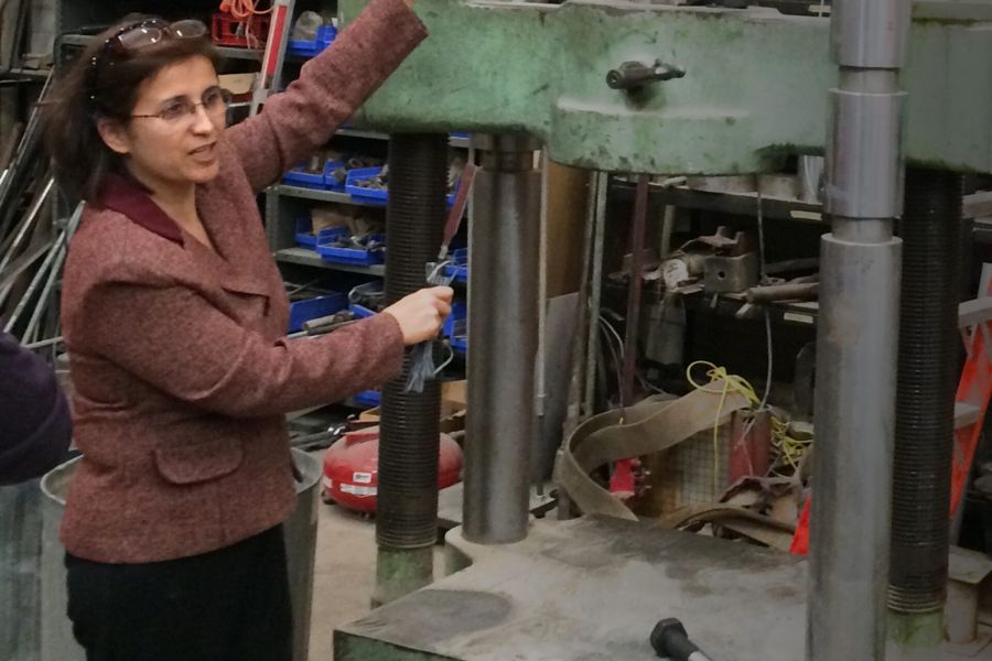 Picture of Shideh Shadravan explaining something with a hydraulic press.