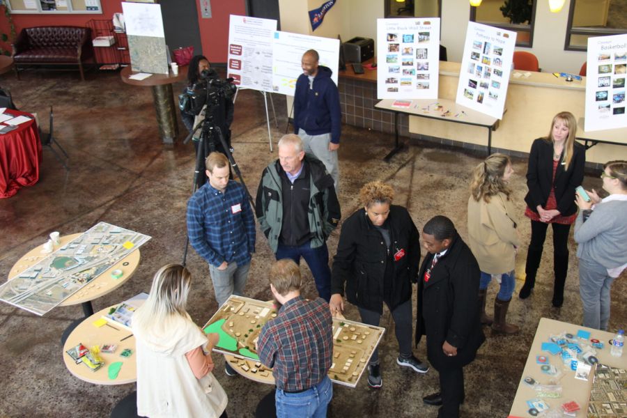 Picture of community event with people interacting around various informational poster and table setups.