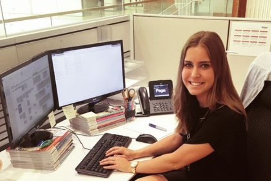 Picture of Emma Smith at a desk during her internship looking to camera smiling.