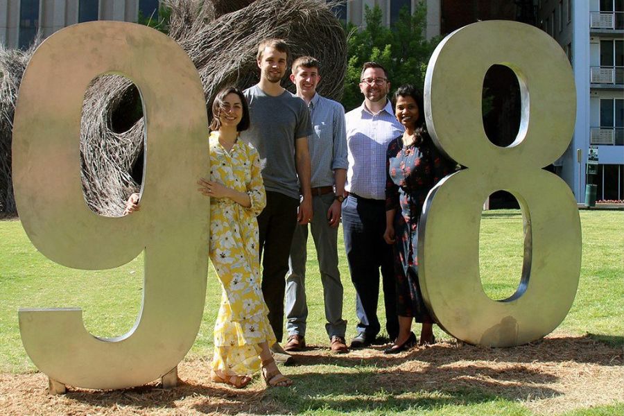 Students in the Master’s of Urban Design program posing for picture with 9 1 8, Tulsa's area code, Art piece.
